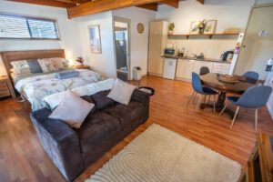 Wattle cottage studio interior with bed, lounge, kitchenette and wooden beams.