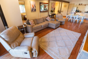 Banksia cottage living area with leather lounge, dining table and kitchen in open-plan layout.