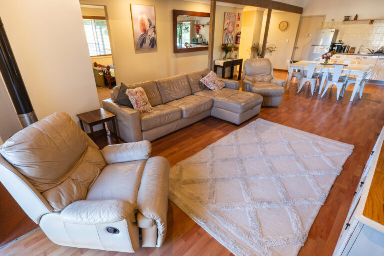 Banksia cottage living area with leather lounge, dining table and kitchen in open-plan layout.