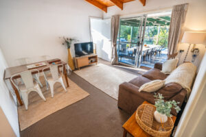 Bluegum cottage lounge with dining table, sofa, and deck access in Scenic Rim.